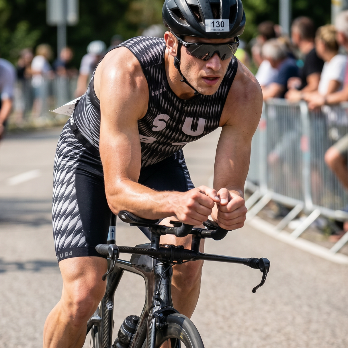 A male triathlete in a black and white patterned Tri-suit on a road with spectators in the background.