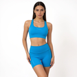 Woman wearing a blue athletic yoga sports bra and shorts on a white background