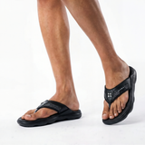 Black sandals worn by a person on a white background